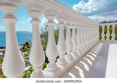 View through balcony on clear blue Aegean sea coast. Traditional white balusters close-up. Greek architecture elements of terrace. Summer country house near Athens, Greece