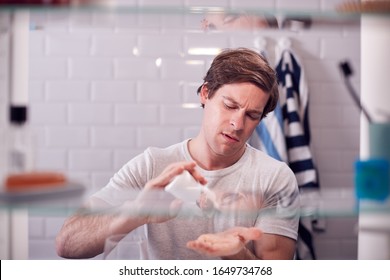 View Through Bathroom Cabinet Of Man Taking Medication From Container