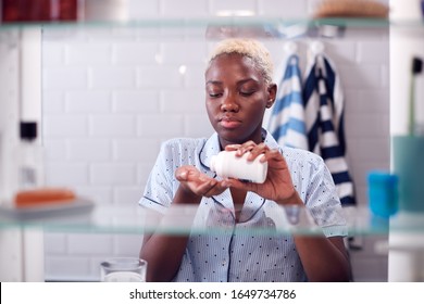 View Through Bathroom Cabinet Of Young Woman Taking Medication From Container