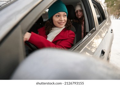 View Through A Blurred Driver's Side Mirror Of Adorable Happy Driver Mom Traveling With Kids By Car On Snow Covered Road On A Beautiful Winter Snowy Day. Winter Holidays, Adventure, Discover Nature