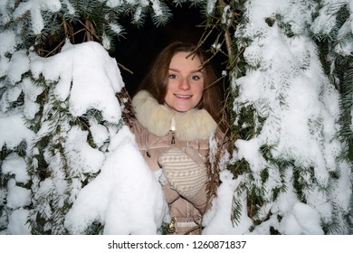 View through the branches of a snow tree on a cheerful young girl