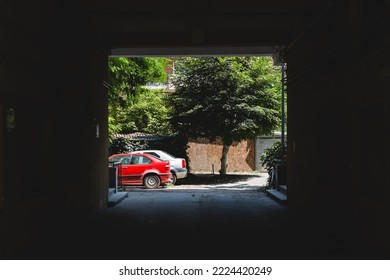 View through a building tunnel to a couple of parked cars