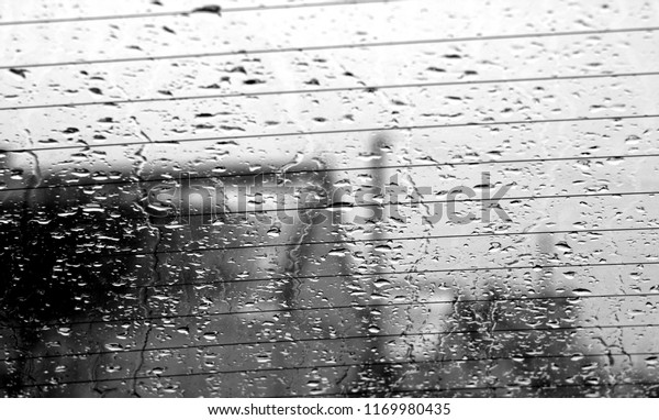 View through car rear window in rain\
drops with blur effect. Seasonal abstract\
background.