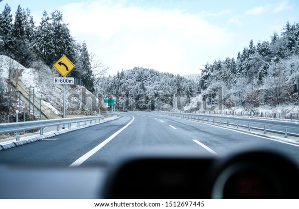 View Through Car\
Windshield, Nice Road in Winter, Snow Covered the Trees, Car\
Dashboard as Foreground
