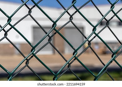 View Through Chain Link Fencing To Defocussed Factory Building