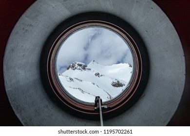 View through the circular window of a refuge of the Picos de Europa national park a winter day. Cantabria, Spain