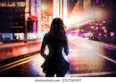 View through glass window with rain drops on blurred  silhouette of a girl on a city street after rain and colorful neon bokeh city lights, night street scene. Focus on raindrops on glass - Powered by Shutterstock