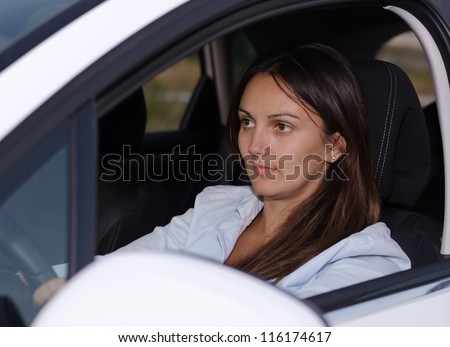 View through the open side window of an attractive woman driving a car concentrating on where she is going