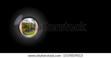 View through peephole in door looking out to entry security surveillance concept solid black background