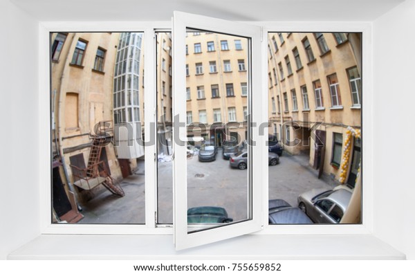 View through the pvc window\
frame on first floor at the narrow quadrangle with parked\
cars