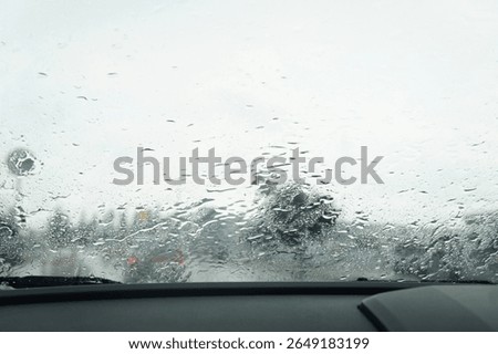 View through a rain-covered windshield from inside a car, capturing the blurry scenery and mood of a rainy day on the road.