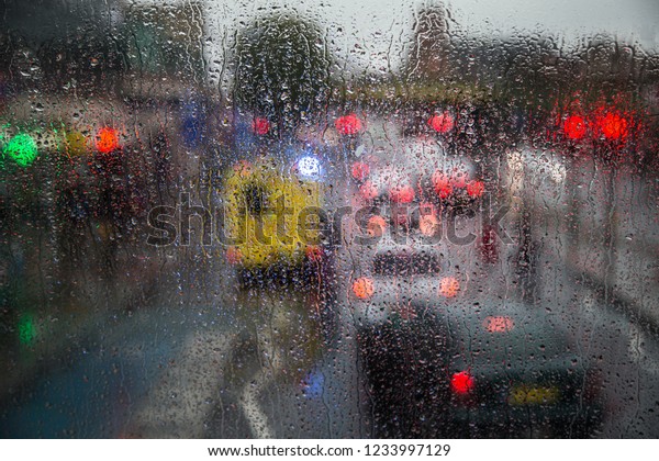 View through the rainy window. Raining weather.\
Car traffic and traffic\
lights.