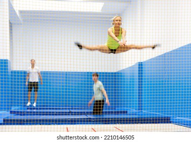 View Through Safety Net Of Group Of Positive People During Training In Trampoline Center. Sport Lifestyle Concept..