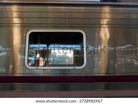 View through a train window with reflections of urban lights, modern subway or commuter train interior detail.