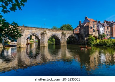 A view through the tree lined shore towards the Elvet Bridge in Durham, UK in summertime