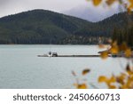 View through the trees of a boat on Lake Minnewanka, Canada.