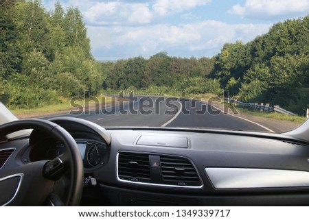 View through the windshield of a car on a country highway in a forested area in summer