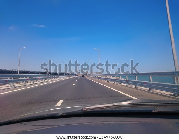 View through the windshield of a moving car.\
Crimea, Russia - June, 8, 2018: Travel on the Crimean bridge during\
its construction. View from the\
car