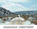 view through the windshield of an SUV, driving the snowcapped and muddy house rock valley dirt road to the buckskin gulch trailhead at the stateline Utah - Arizona, United States of America, USA