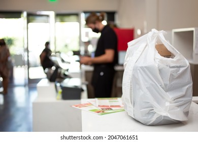 A View Of A To-go Plastic Bag Full Of Take-out Food Orders, Seen On A Restaurant Counter.