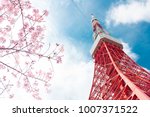View of Tokyo tower and pink cherry blossom(sakura) with blue sky during winter season of Japan in uprisen angle.