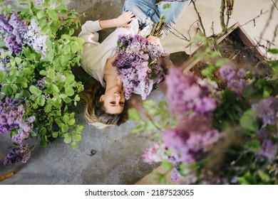 view top. an attractive blonde in a white shirt and jeans on the floor with lilac flowers. profession of a florist. fragrances and perfumes for the home. femininity and tenderness. feminine beauty. - Shutterstock ID 2187523055