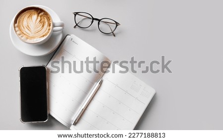 View the top of the background with diary notes and cell phones, pens, glasses, coffee cups, and copy space in the gray business table