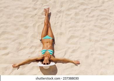 View From Top Of Beautiful Girl In Bikini Wearing White Hat And Sunglasses On Beach Sand In Summer