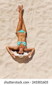 View From Top Of Beautiful Woman In Bikini With White Hat And Sunglasses On Beach Sand In Summer