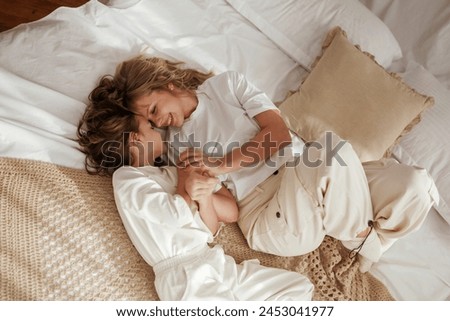 View from the top, lying down on bed. Mother with daughter are at home together.
