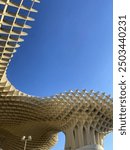 View of the top of Metropol Parasol, or Setas de Seville, against a blue sky.