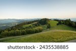 View from the top of Pfänder mountain at sunset - view at green alpine meadows, Bregenz Forest and range of Vorarlberg alpine summits in the background. Clear sky without gradient, calm evening.