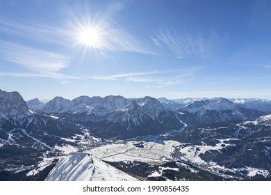 View from top of a mountain to the valley of Ehrwald at a beautiful day in winter  Wild snowy alpine landscape with sun and blue sky  Tirol, Austria - Powered by Shutterstock