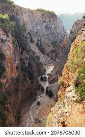 View from the top of a narrow deep mountain gorge with sheer stone walls and rare bushes, Aradena Gorge, Crete, Greece - Shutterstock ID 2076706030