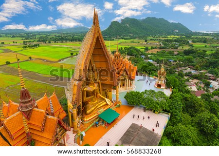 A view from the top of the pagoda, golden buddha statue with rice fields and mountain, Tiger Cave Temple (Wat Tham Seua) Thai and Chinese temples  in Kanchanaburi province.