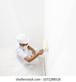 View from top painter man at work with a paint roller, wall painting concept