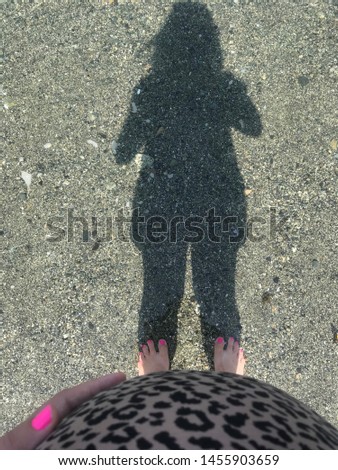 view from top to pregnant woman belly and her shadow and feet