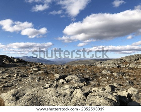 View from the top of Saana mountain in Kilpisjarvi, Lapland, Finland. Hiking in Northern Europe during fall. Autumn colors on the ground. Blue sky, clouds. No people. Rocky road, path for hikers.