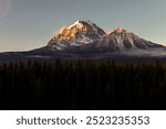 view of the top of two mountains  under the first rays of sunshine in the morning of a clear summer day with low clouds creating a dramatic effect