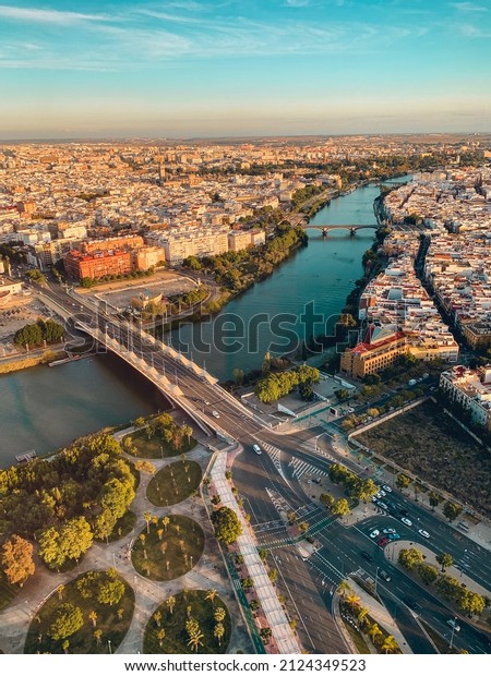 View from Torre\
Seville. Aerial view of Seville. Guadalquivir river across two\
bridges. Triana bridge. Barquera bridge. Seville cathedral. Sunset \
skyline Seville.