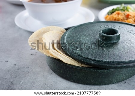 A view of a tortilla warmer with some corn tortillas sticking out.