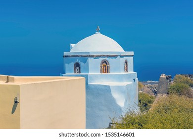 A View Towards A White Domed Church From The Castle Ruins In Pyrgos, Santorini In Summertime