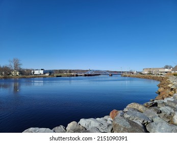 The View Of Town Bridge From Along The Wooden Dock Next To The Arched Structure. The Small Drawbridge Is Modern And Blue. 