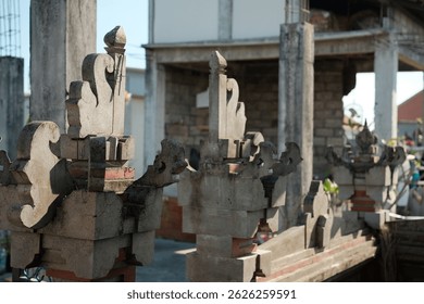 A view of traditional Balinese stone carvings or architectural ornaments, showcasing the intricate patterns and weathered texture of the stone work on what appears to be a gate or fence structure