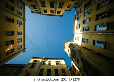 A view of a traditional courtyard-well in Saint Petersburg, Russia. The enclosed, narrow space is framed by high historic buildings, with a glimpse of the sky overhead. - Powered by Shutterstock