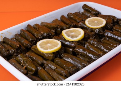 View of traditional Turkish Cuisine wraps and lemon slices on a boat plate, shot with selective focus from opposite or side angle, isolated on orange background.