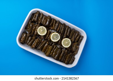 View of traditional Turkish Cuisine wraps and lemon slices on a boat plate, shot with selective focus from overhead angle, isolated on blue background.