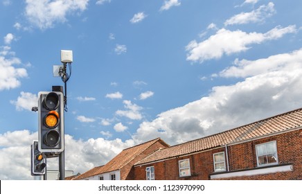 View Of A Traffic Light Illuminated In Yellow In The Middle Of A Small English Town, UK