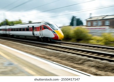 A view from a train station platform as a passenger train flies past at high speed.