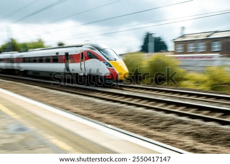 A view from a train station platform as a passenger train flies past at high speed.